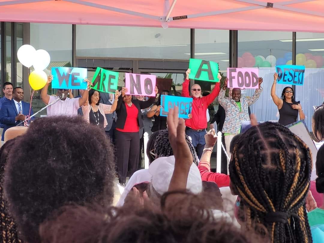 Rise Community Market board members holding We are no longer a food desert signs